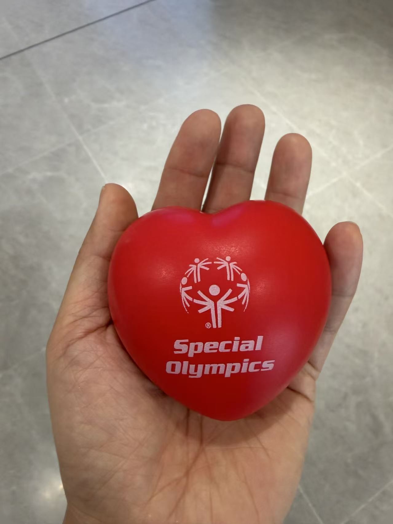 A hand holding an activity ball marked with the Special Olympics logo